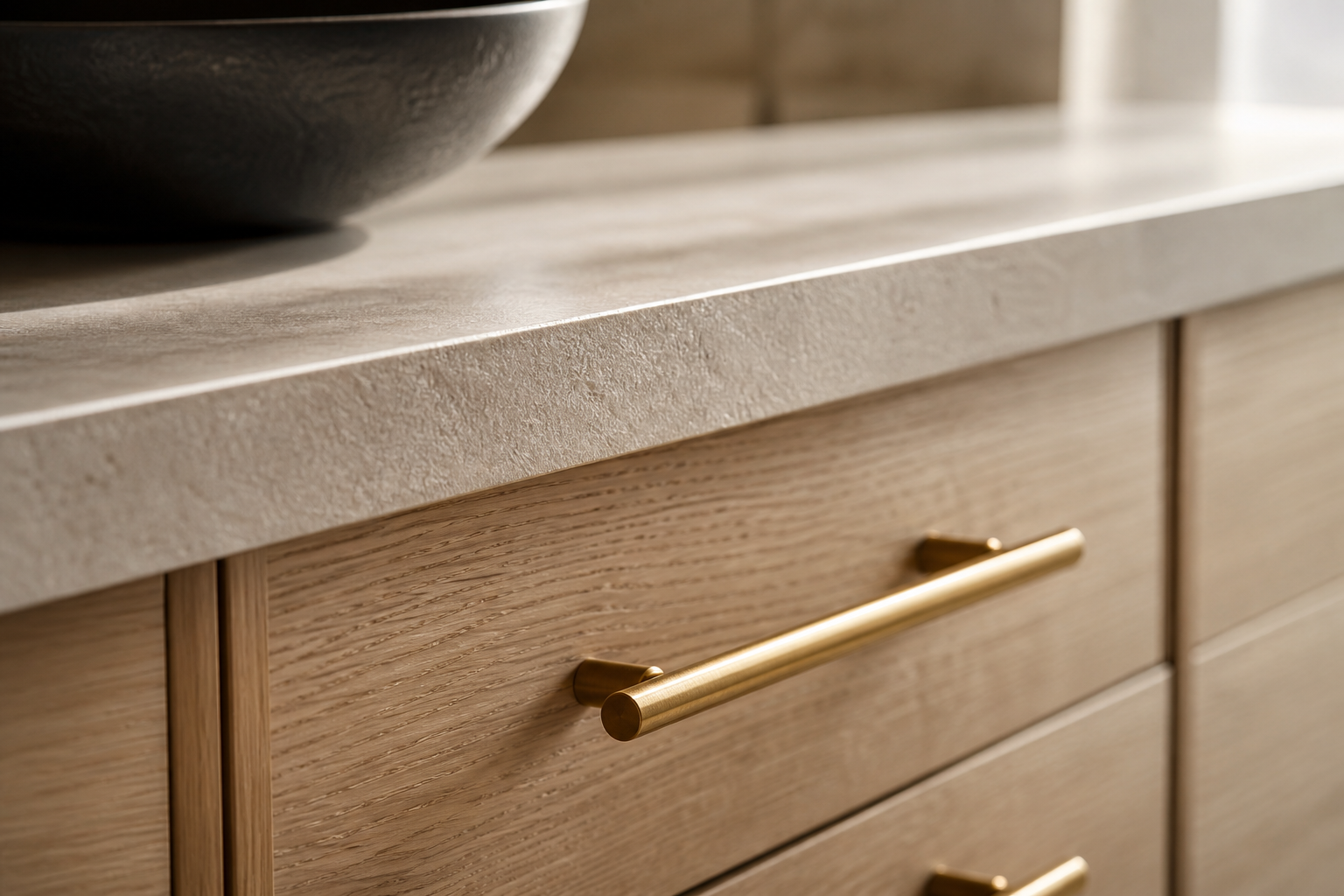 Close-up of white oak cabinetry, brushed brass hardware, and honed stone countertop in a Calgary kitchen renovation